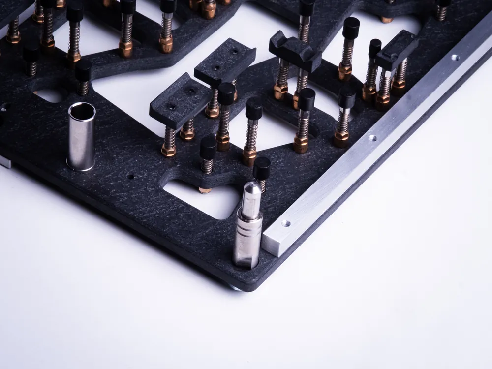 Hold-down pins and masking inserts along the edge of a wave solder carrier